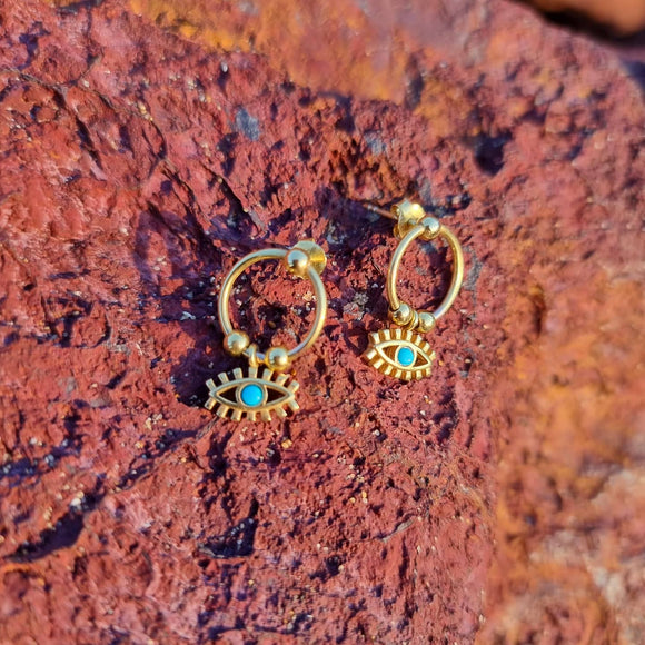 The Evil Eye Dangled Earrings are a delicate yet striking piece. Featuring our favourite Ancient Symbol; The Evil Eye which is believed to represent protection from the evil glare. This piece with a beautiful turquoise center dangles off a circular gold ring which rests flat on the ear lobe. Wear them with a sleeked back pony to best feature them and pair them with your favourite necklace.   Material:  18K Gold Vermeil with a Sterling Silver base  Dimension:  *enter specs here*